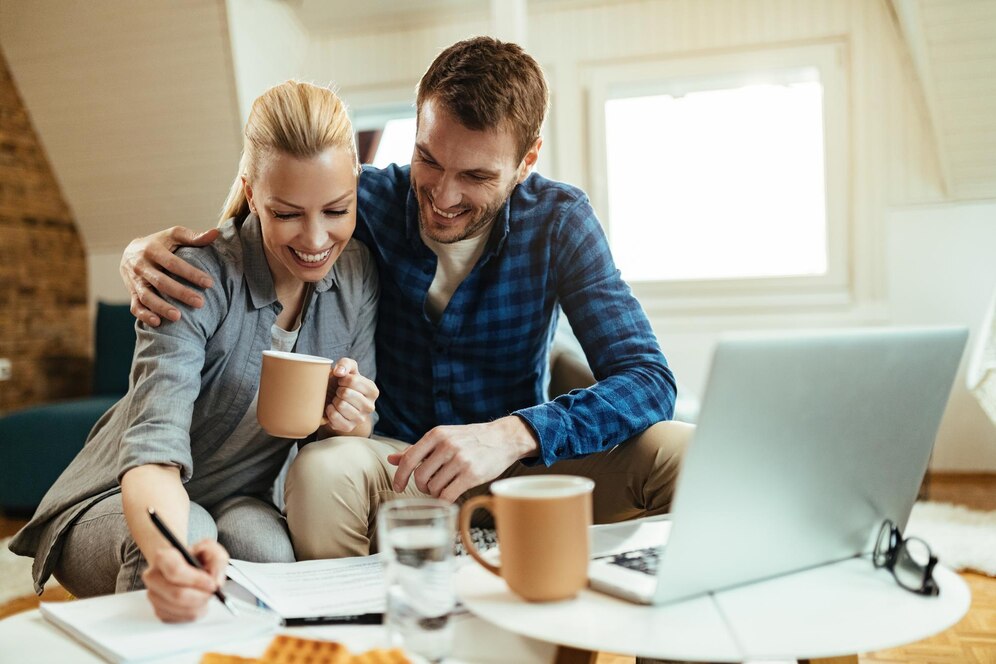 happy-couple-writing-notes-while-going-through-home-finances-their-coffee-time